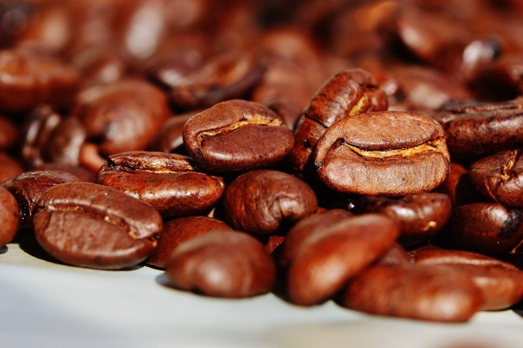 Close-up of roasted coffee beans with rich, dark brown color and oily sheen.